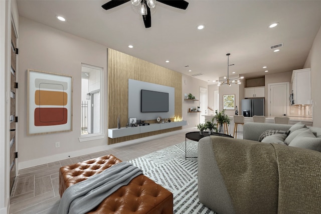 living room featuring ceiling fan with notable chandelier and plenty of natural light