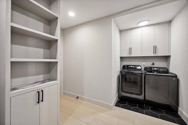 clothes washing area featuring washer and clothes dryer and cabinets