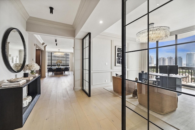 hall with an inviting chandelier, crown molding, light hardwood / wood-style floors, and french doors