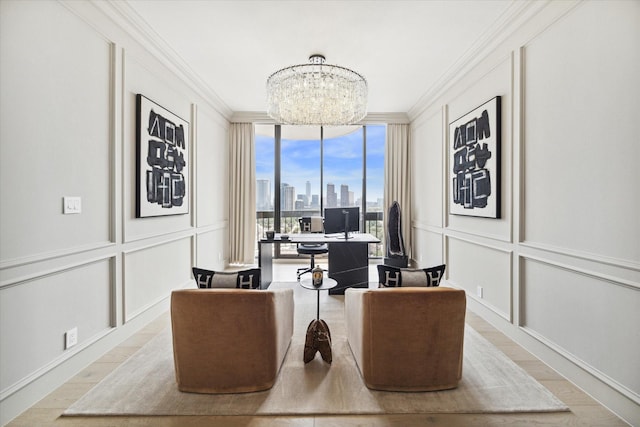 home office with crown molding, light wood-type flooring, an inviting chandelier, and a wall of windows