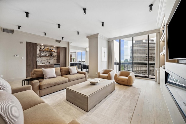 living room with expansive windows, a fireplace, crown molding, and light hardwood / wood-style floors