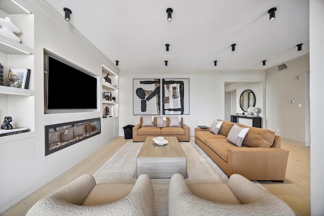 living room with ornamental molding, light hardwood / wood-style floors, and built in features