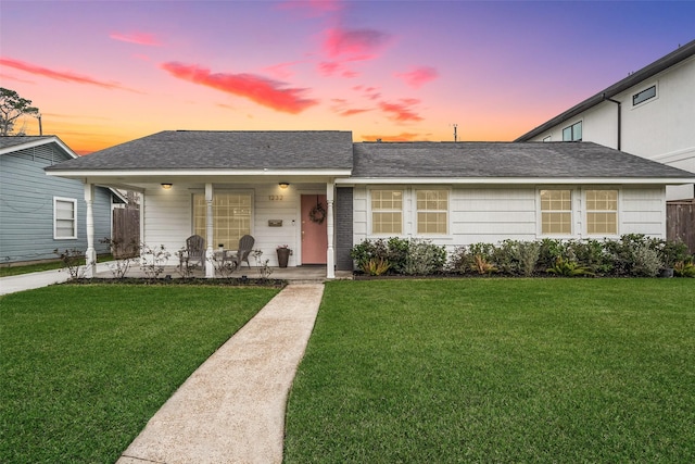 single story home with covered porch and a lawn