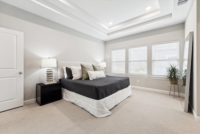 bedroom featuring a tray ceiling and light carpet