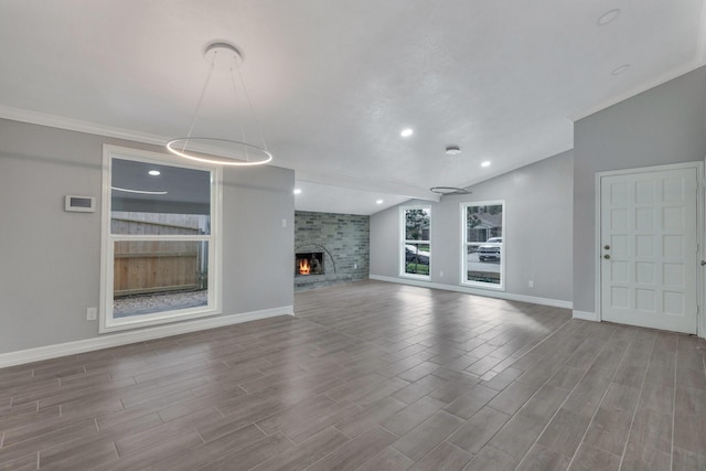 unfurnished living room with hardwood / wood-style flooring, vaulted ceiling, ornamental molding, and a fireplace