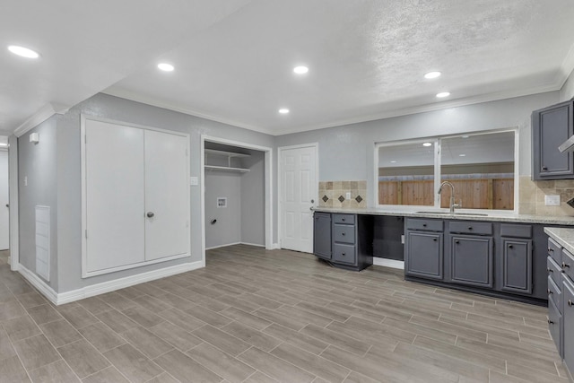 kitchen featuring tasteful backsplash, sink, gray cabinetry, light stone counters, and crown molding