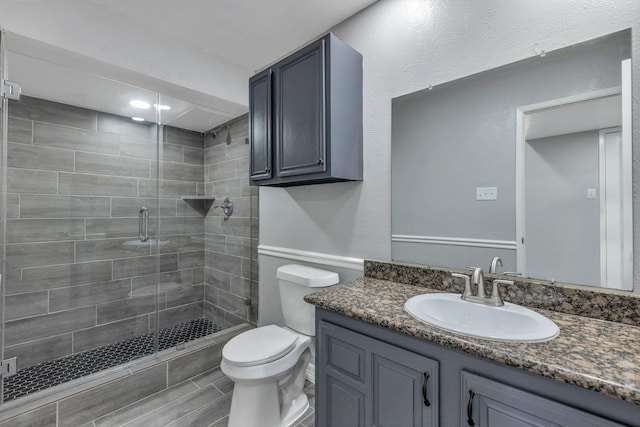 bathroom featuring vanity, toilet, and a shower with shower door