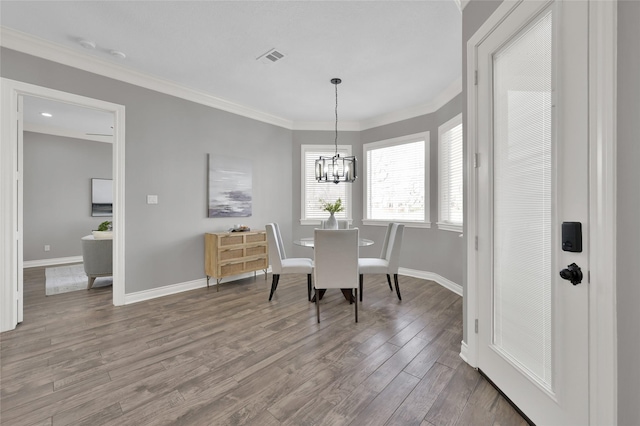 dining area with ornamental molding, hardwood / wood-style floors, and an inviting chandelier