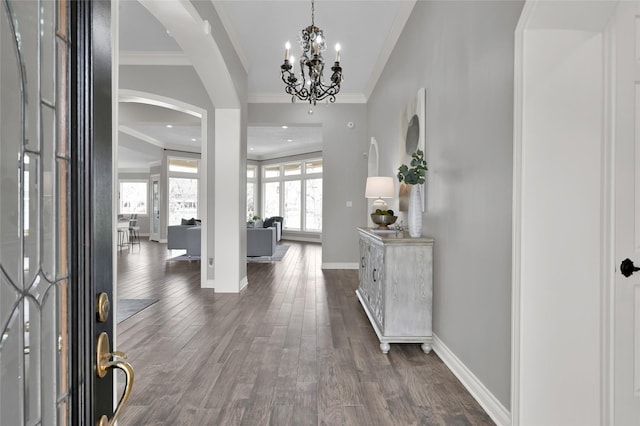 foyer with ornamental molding, dark wood-type flooring, and a chandelier