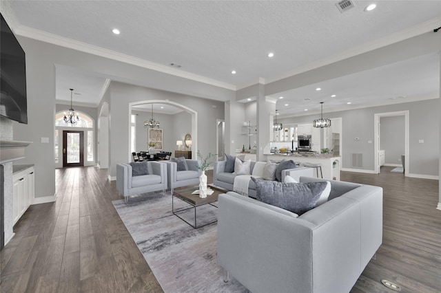 living room with an inviting chandelier, hardwood / wood-style floors, crown molding, and a textured ceiling