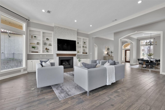 living room featuring dark hardwood / wood-style flooring, ornamental molding, a large fireplace, and a textured ceiling