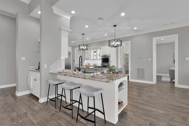 kitchen with decorative light fixtures, white cabinets, ornamental molding, kitchen peninsula, and light stone countertops