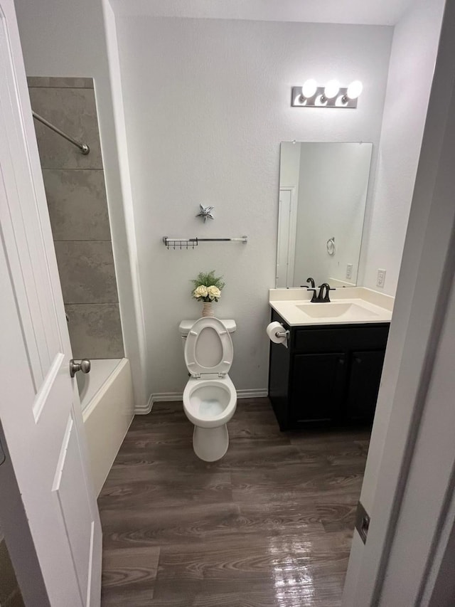 full bathroom featuring vanity, tiled shower / bath, wood-type flooring, and toilet