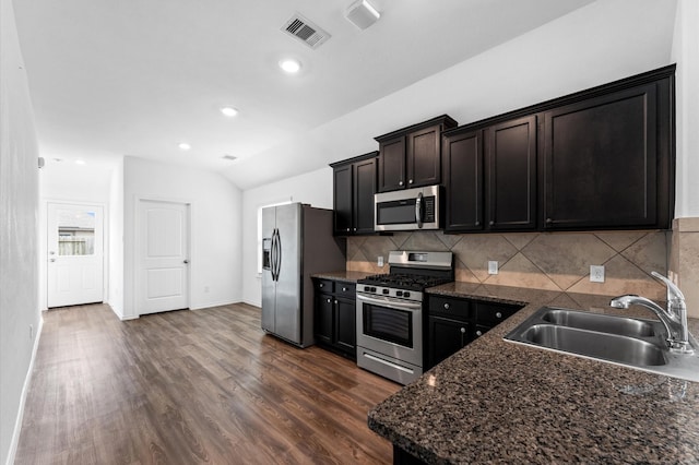 kitchen featuring stainless steel appliances, dark hardwood / wood-style flooring, sink, vaulted ceiling, and tasteful backsplash