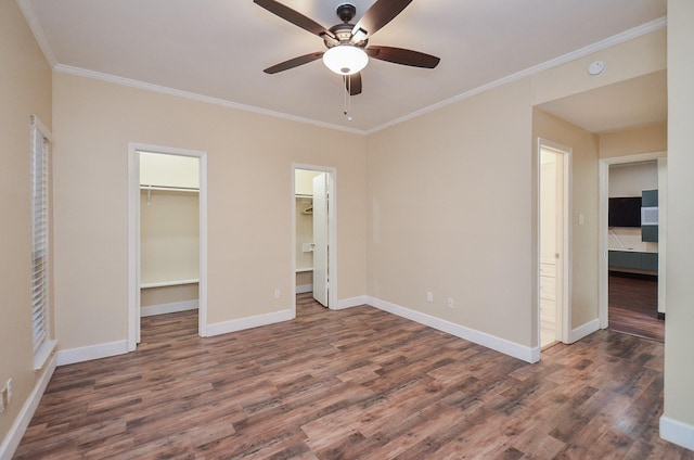 unfurnished bedroom with dark hardwood / wood-style floors, a spacious closet, ceiling fan, crown molding, and a closet