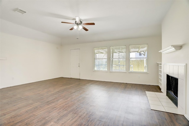 unfurnished living room with visible vents, dark wood-type flooring, baseboards, ceiling fan, and a tile fireplace