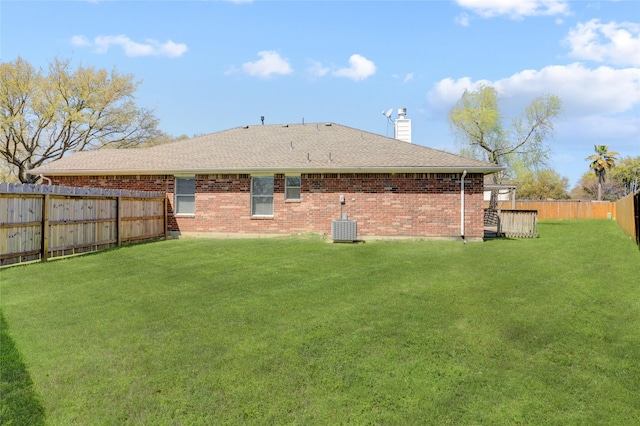 back of house featuring a yard, central AC unit, brick siding, and a fenced backyard