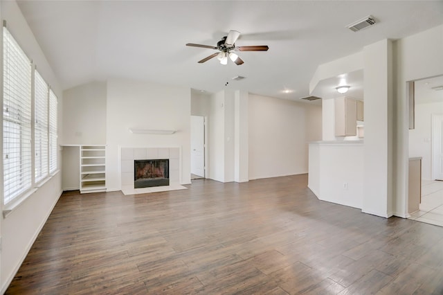 unfurnished living room featuring visible vents, a tile fireplace, a ceiling fan, and wood finished floors