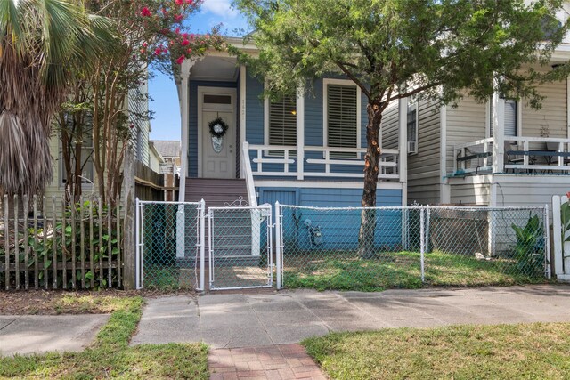 1621 Ursuline St, Galveston, TX 77550 - shotgun-style home with covered porch, a gate, and a fenced front yard