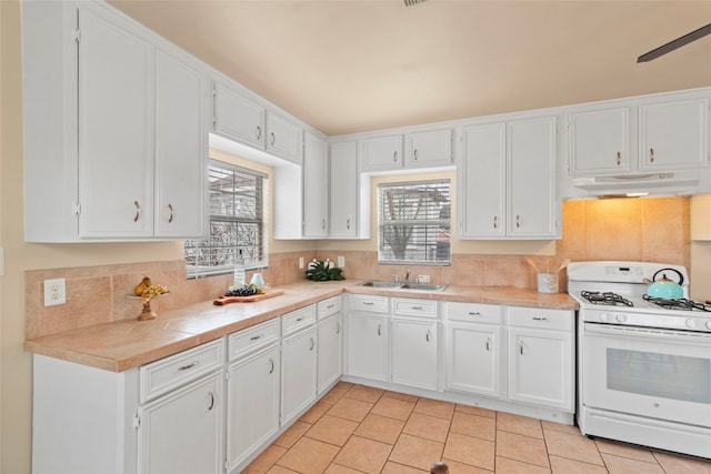 1621 Ursuline St, Galveston, TX 77550 - kitchen featuring white cabinets, a sink, white gas stove, and under cabinet range hood