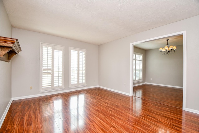 spare room featuring hardwood / wood-style flooring, a textured ceiling, and a chandelier