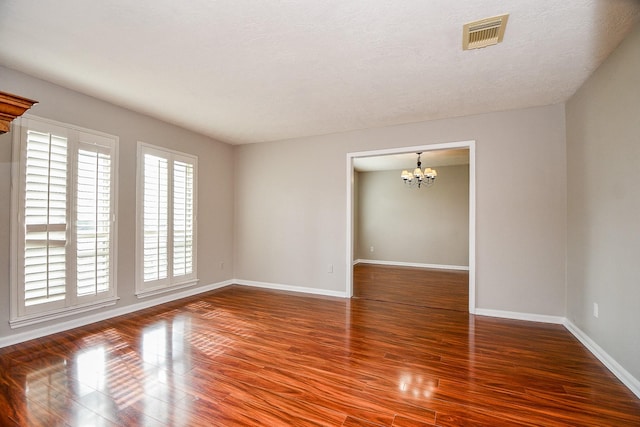 spare room with a chandelier, hardwood / wood-style floors, and a textured ceiling