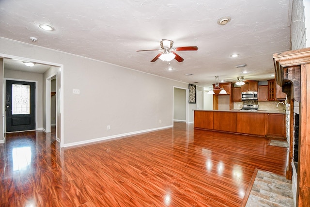 unfurnished living room with dark wood-type flooring, ceiling fan, and sink