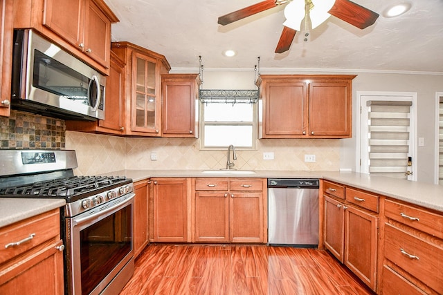 kitchen featuring sink, appliances with stainless steel finishes, tasteful backsplash, ornamental molding, and light wood-type flooring