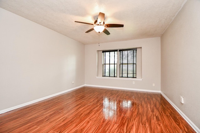 empty room with dark wood-type flooring, ceiling fan, and a textured ceiling