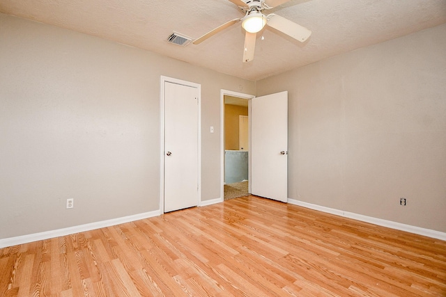 spare room with a textured ceiling, ceiling fan, and light wood-type flooring