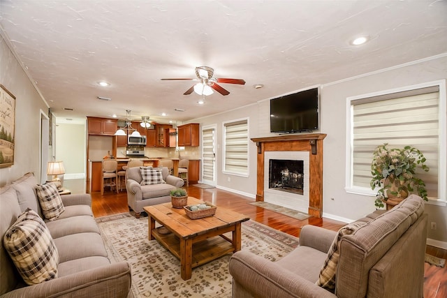 living room featuring crown molding, ceiling fan, and light hardwood / wood-style flooring