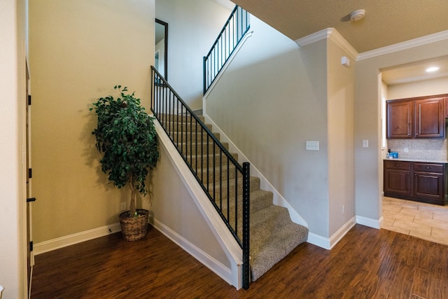 staircase with hardwood / wood-style flooring and ornamental molding