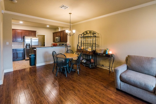 dining area featuring crown molding, hardwood / wood-style floors, and a chandelier