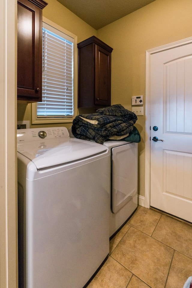 laundry room featuring cabinets, washing machine and dryer, and light tile patterned floors