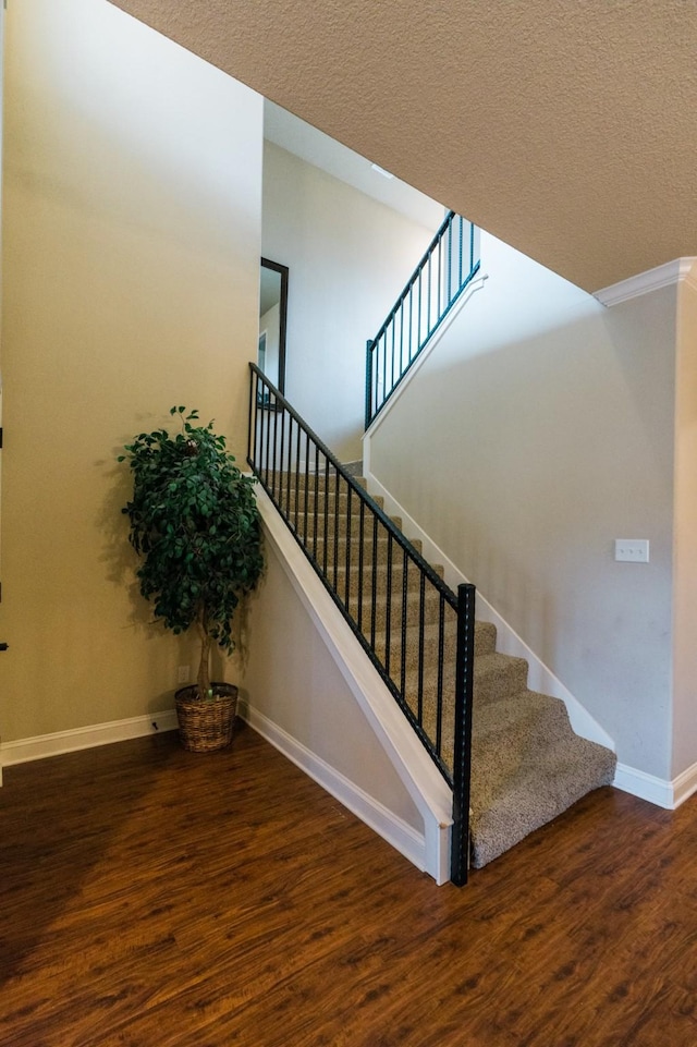 staircase featuring wood-type flooring and a textured ceiling