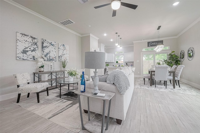 living room featuring ornamental molding, ceiling fan with notable chandelier, and light wood-type flooring