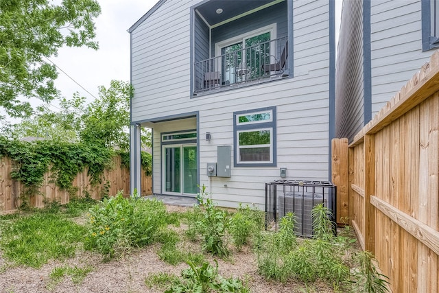 rear view of house featuring cooling unit and a balcony