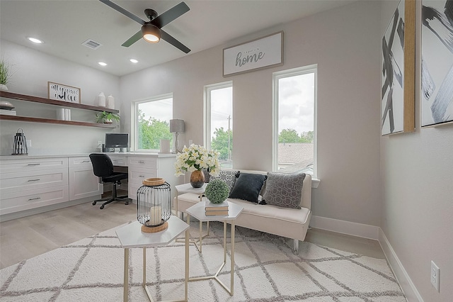 home office with ceiling fan, built in desk, and light hardwood / wood-style floors