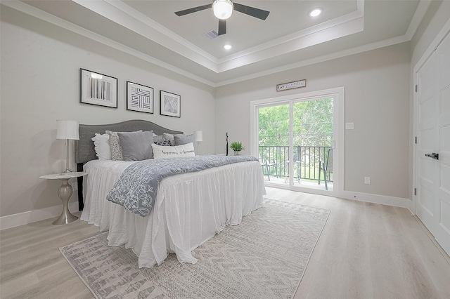 bedroom with crown molding, a raised ceiling, light wood-type flooring, and access to outside