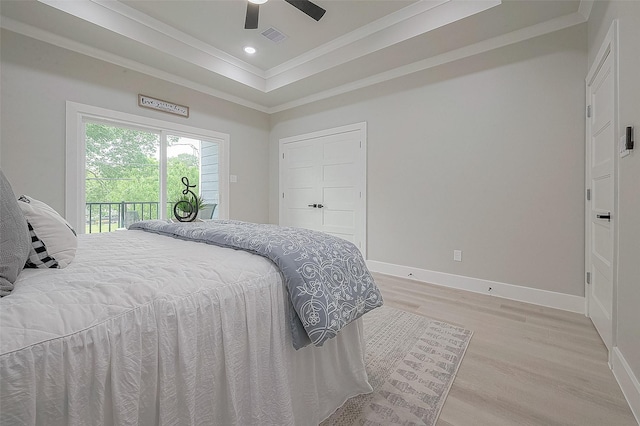 bedroom featuring access to exterior, a tray ceiling, ornamental molding, and light hardwood / wood-style floors