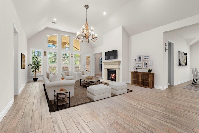 living room featuring a lit fireplace, light wood-type flooring, high vaulted ceiling, and visible vents