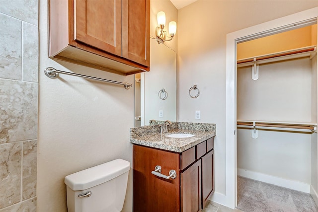 bathroom featuring vanity, toilet, and a spacious closet