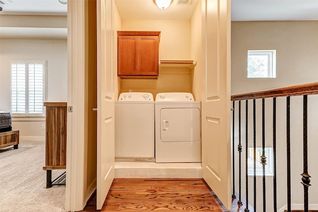 laundry room featuring cabinets, washer and dryer, and light colored carpet