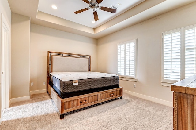 bedroom with ceiling fan, a raised ceiling, and light carpet