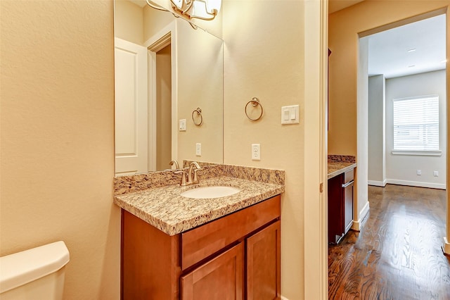 bathroom featuring wood-type flooring, vanity, and toilet