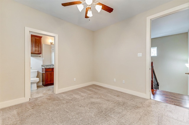 empty room featuring baseboards, a ceiling fan, and light carpet