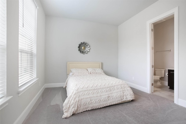 bedroom with connected bathroom and light colored carpet