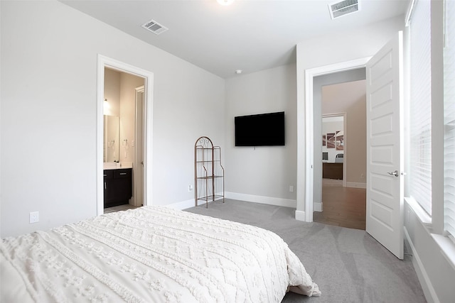 bedroom with light carpet and connected bathroom