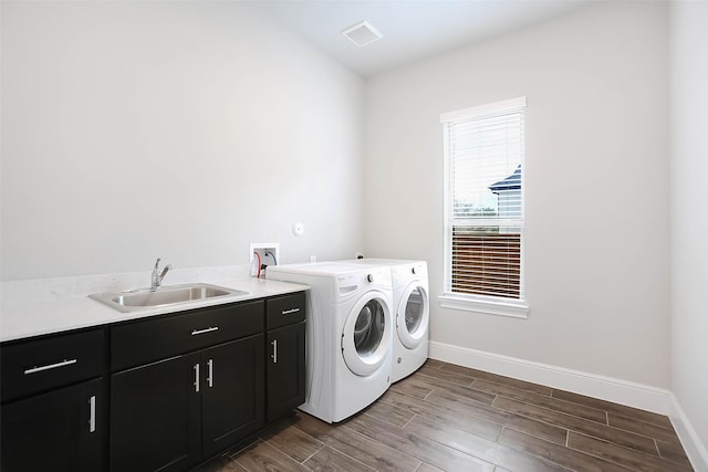 laundry room with sink, washing machine and dryer, and cabinets