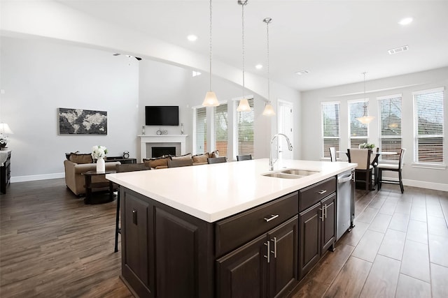 kitchen featuring sink, dishwasher, hanging light fixtures, a kitchen breakfast bar, and an island with sink